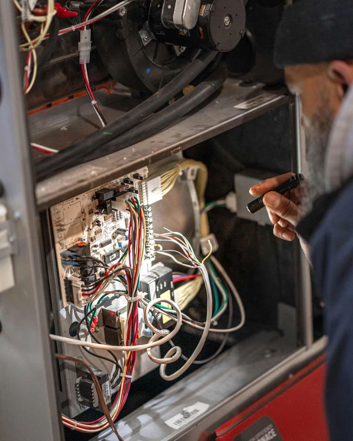 HVAC technician standing in front of a residential metal furnace unit during service